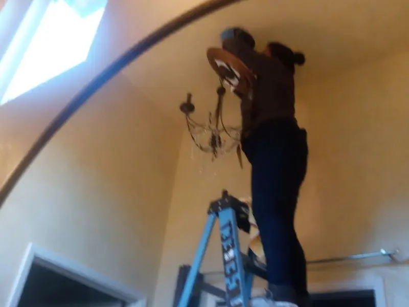 Electrician installing a chandelier in a Junction City residence